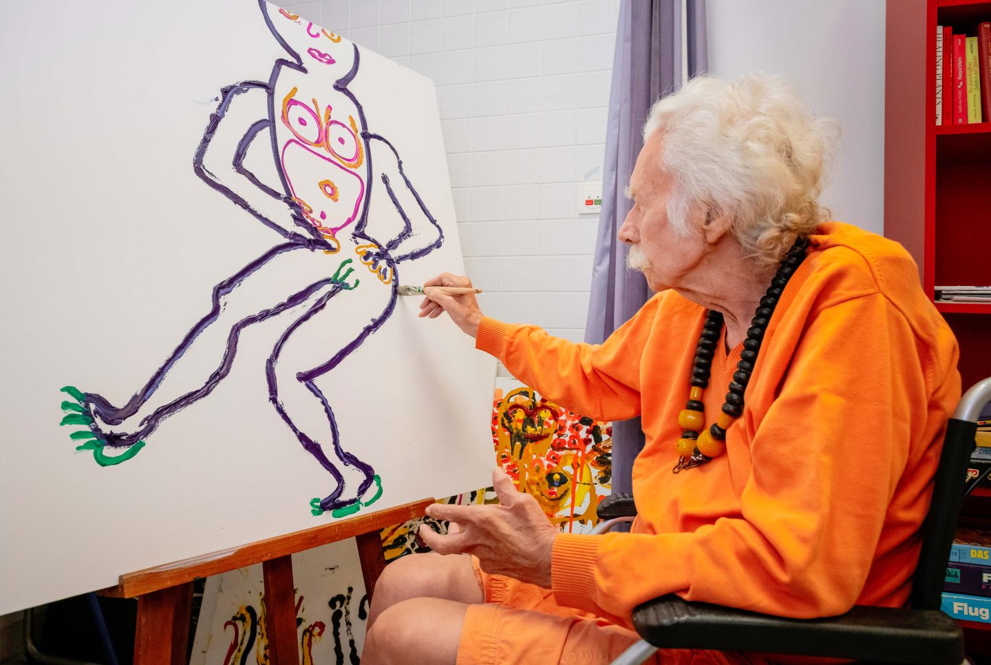 Ein Herr sitzt im Atelier und bemalt eine Leinwand